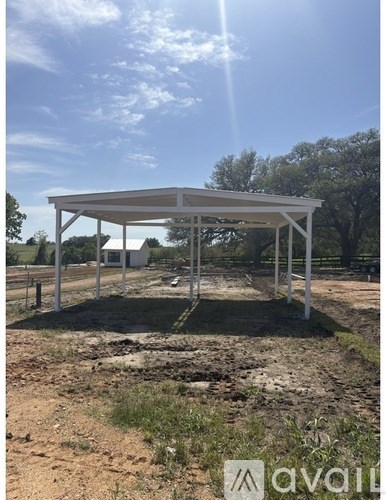 A white metal structure is being built in a field.