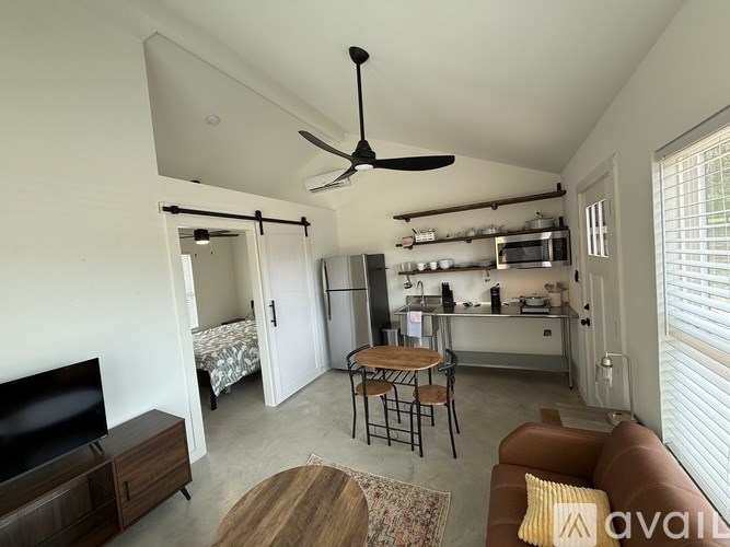 A living room with a brown couch, a television, and a ceiling fan.