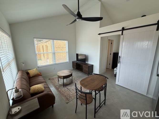 A living room with a brown couch, a wooden coffee table, and a ceiling fan.