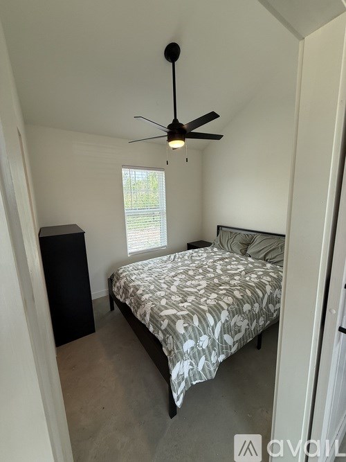 A bedroom with a bed, a ceiling fan, and a window.