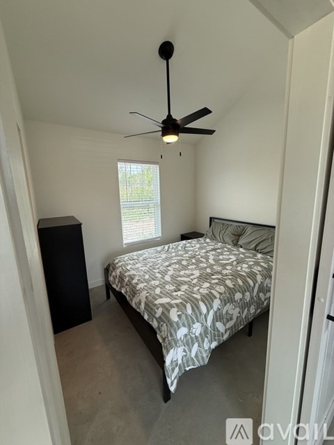 A bedroom with a bed, a ceiling fan, and a window.