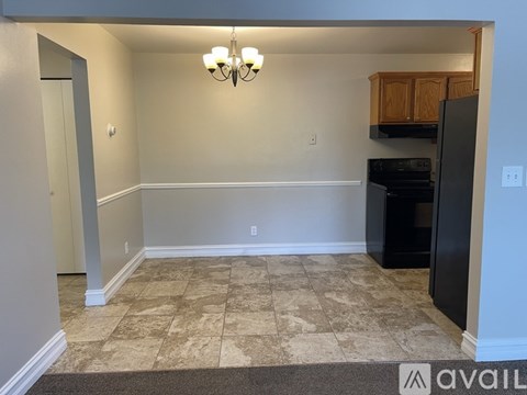 A kitchen area with a black refrigerator and a chandelier.