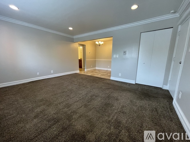 A spacious room with a carpeted floor and white walls.
