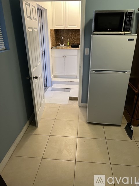 A kitchen with a white refrigerator and a microwave on top of it.