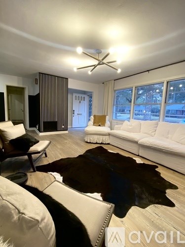 A living room with a white couch and a brown cowhide rug.