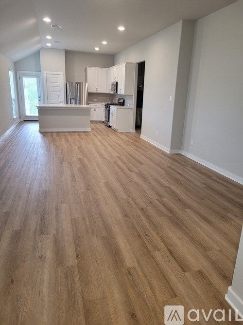 A spacious kitchen and living room with wooden flooring.