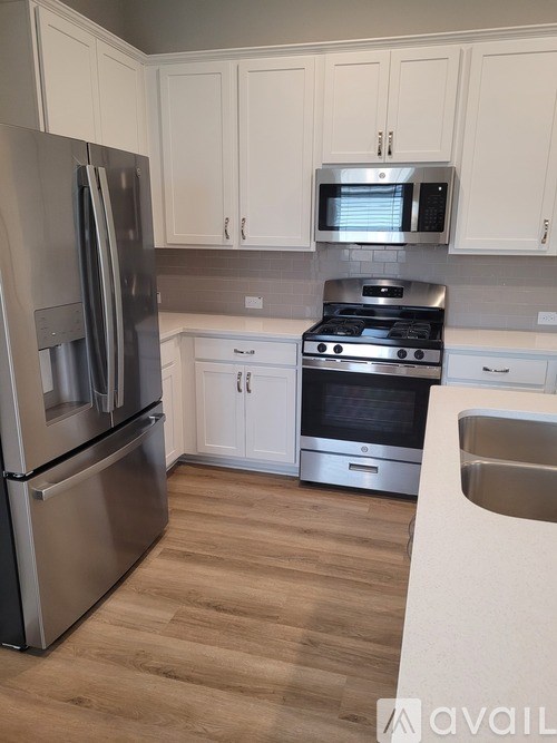 A kitchen with a stainless steel refrigerator, microwave, and oven.