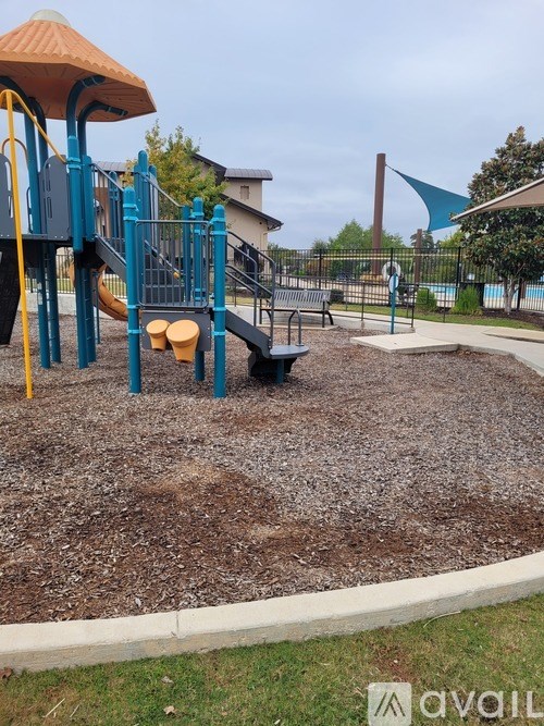 A playground with a slide, swings, and a seesaw.