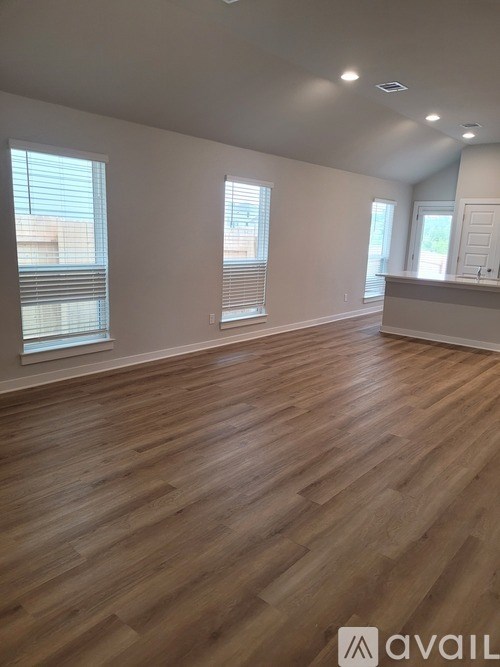 A room with wooden flooring and windows.