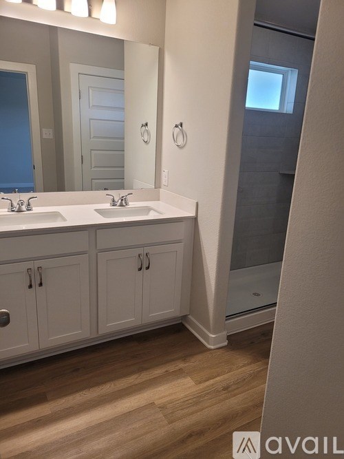 A bathroom with a double sink vanity and a glass shower door.