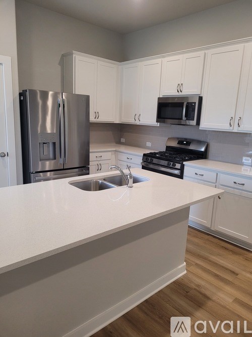 A kitchen with white cabinets and a stainless steel refrigerator.
