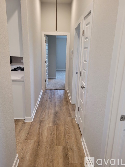 A long hallway with white walls and wood flooring.