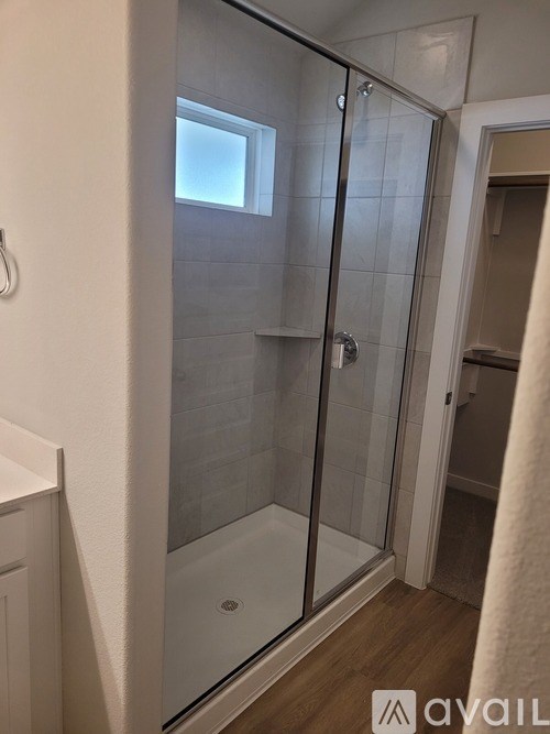 A bathroom with a glass shower door and a white towel hanging on the door.