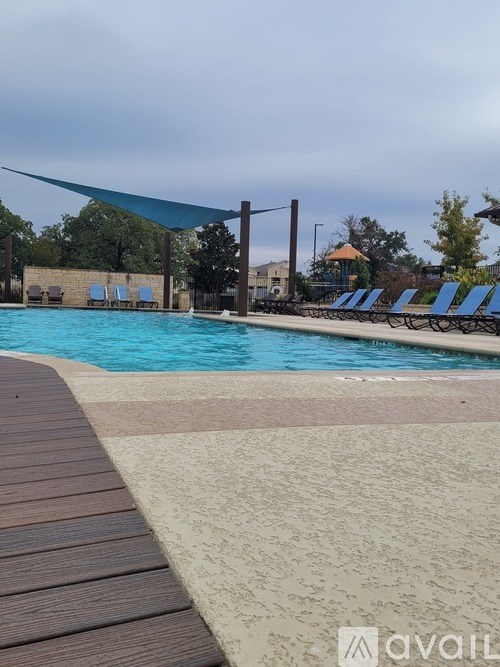 A pool with a blue shade and a wooden deck.