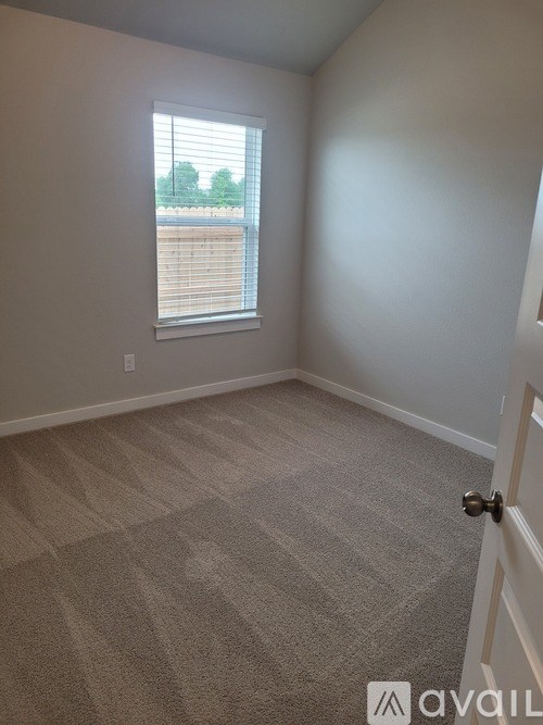 A room with a carpeted floor and a window with blinds.