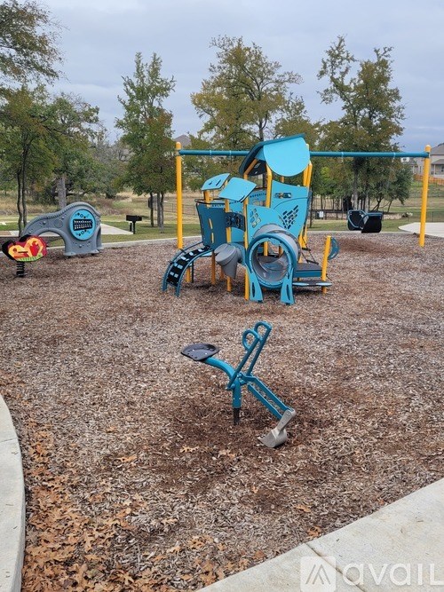 A playground with a blue and yellow play structure and a seesaw.