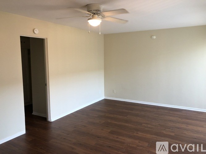 A room with a ceiling fan and wooden flooring.
