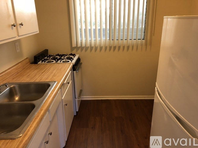 A kitchen with a stove, sink, and cabinets.