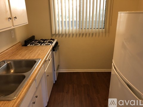 A kitchen with a stove, sink, and cabinets.