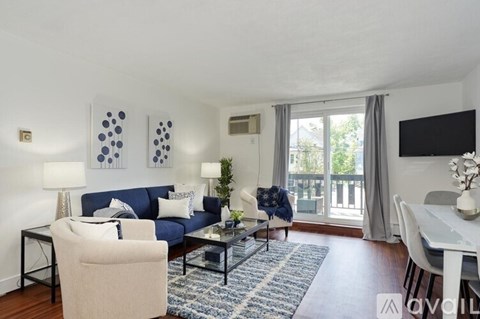 A living room with a blue couch and a white chair.