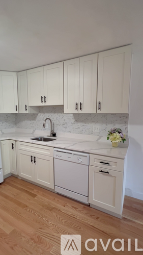 A kitchen with white cabinets and a marble backsplash.