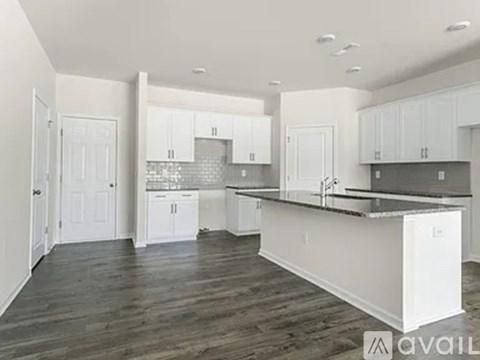 A kitchen with white cabinets and a black countertop.