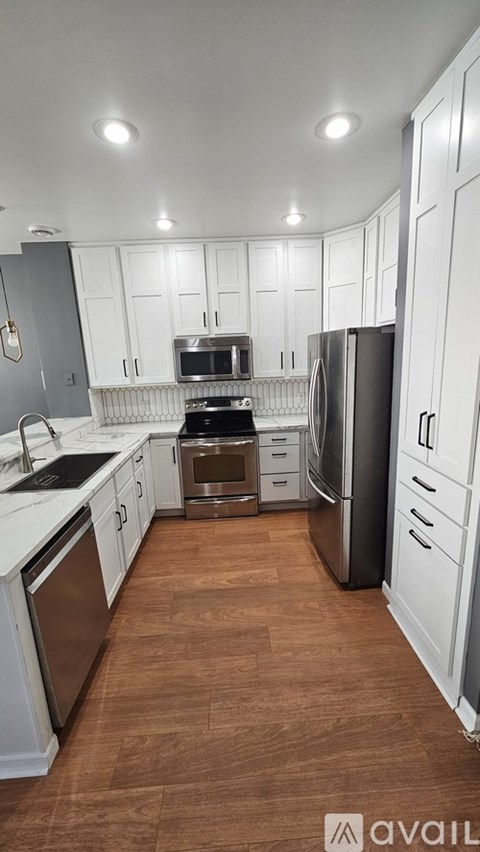 A kitchen with white cabinets and a wooden floor.