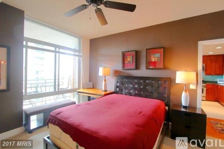 A bedroom with a red bedspread and a ceiling fan.