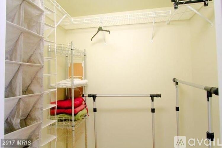 A room with a white wall and a clothes rack.