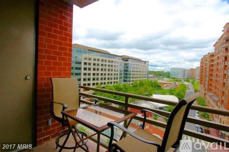 A balcony with a table and two chairs overlooks a cityscape.