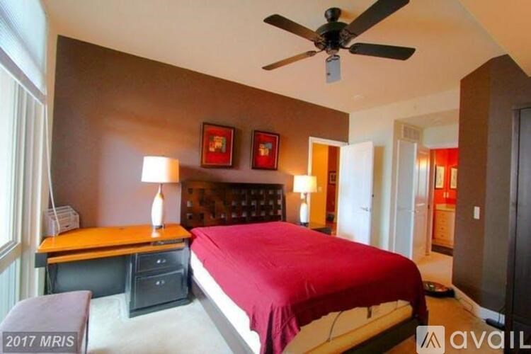 A bedroom with a bed, desk, and ceiling fan.