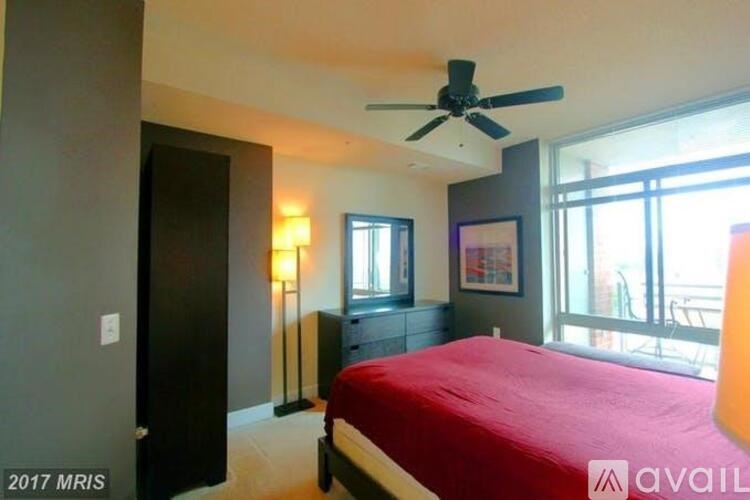 A bedroom with a red bedspread and a ceiling fan.