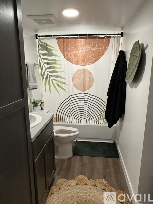 A bathroom with a toilet, sink, and a shower curtain with a leaf design.
