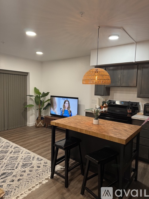 A modern kitchen with a wooden table and bar stools.