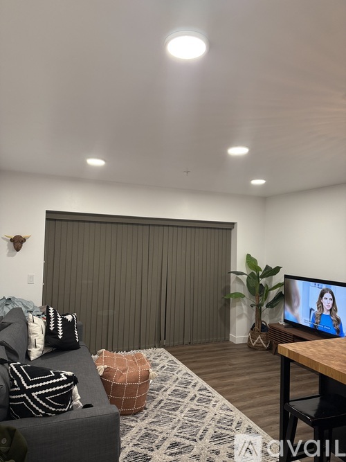 A living room with a grey couch and a television on a wooden stand.