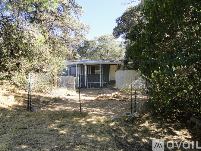 A house surrounded by a fence and trees.