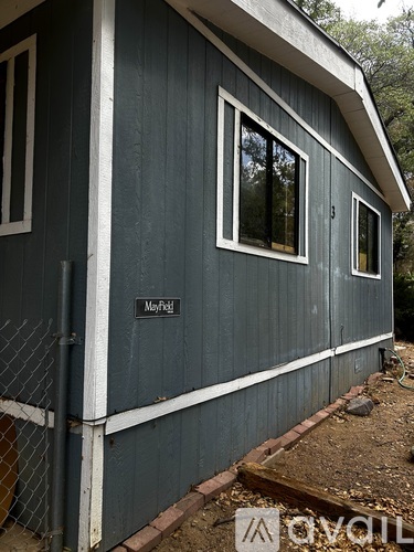 A small house with a fence and a sign that says Mayfield.