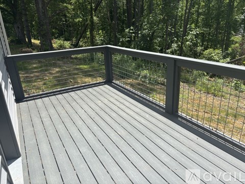 A deck with a metal railing and a view of a wooded area.