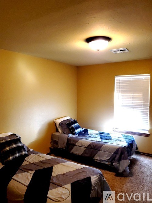 Two twin beds in a room with yellow walls.
