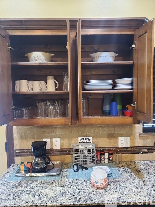 A kitchen with a granite countertop and a cabinet with plates and cups.