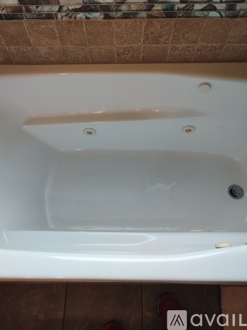 A white bathtub with a faucet and a drain.