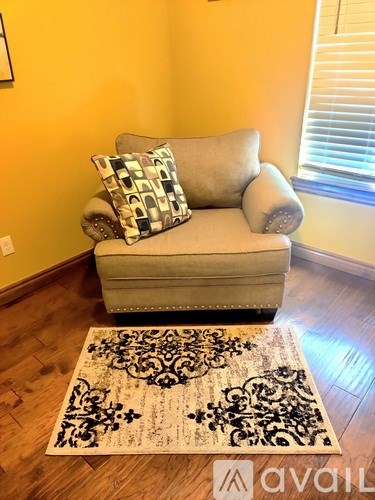 A grey couch with a pillow and a rug in front of it.