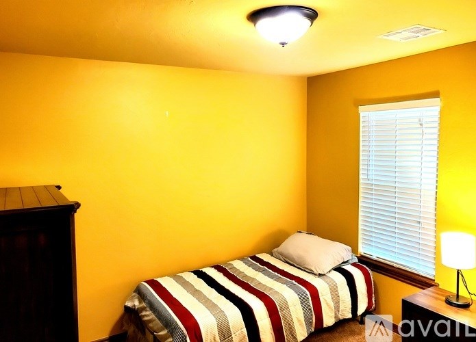 A bedroom with a bed, a lamp, and a window.