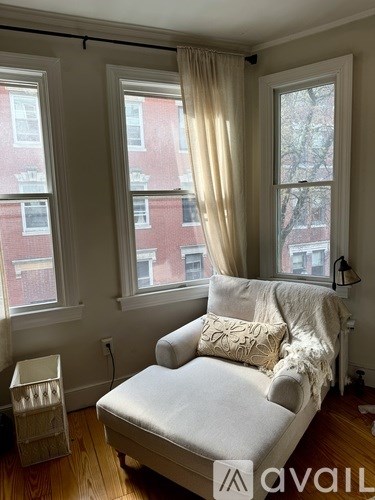 A living room with a white couch and a window with curtains.