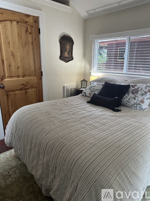 A bedroom with a bed, pillows, and a wooden door.
