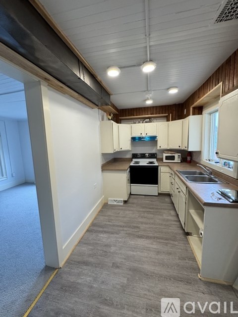 A kitchen with white cabinets and a grey floor.