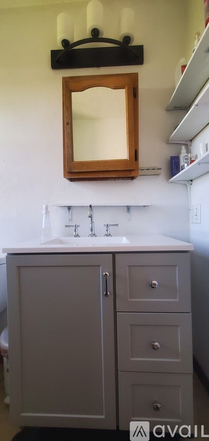 A bathroom with a white sink and a wooden framed mirror.