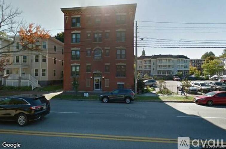 A street view of a parking lot with cars and a building.