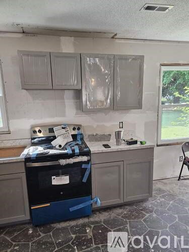A kitchen undergoing renovation with cabinets and appliances covered in plastic.