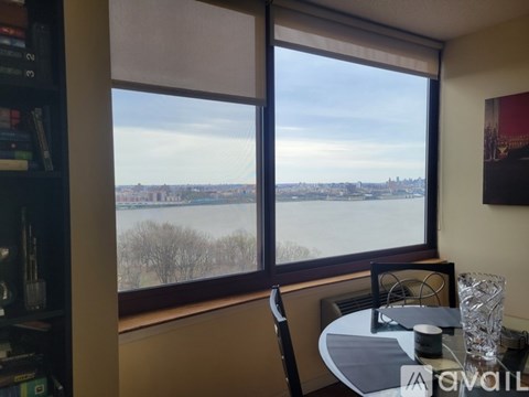 A room with a table and chairs in front of a window overlooking a body of water.